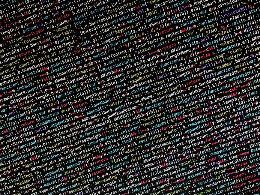 A close-up view of a computer screen displaying lines of coloured programming code on a black background. The code appears to include syntax highlighting with green, blue, red, and purple elements, an